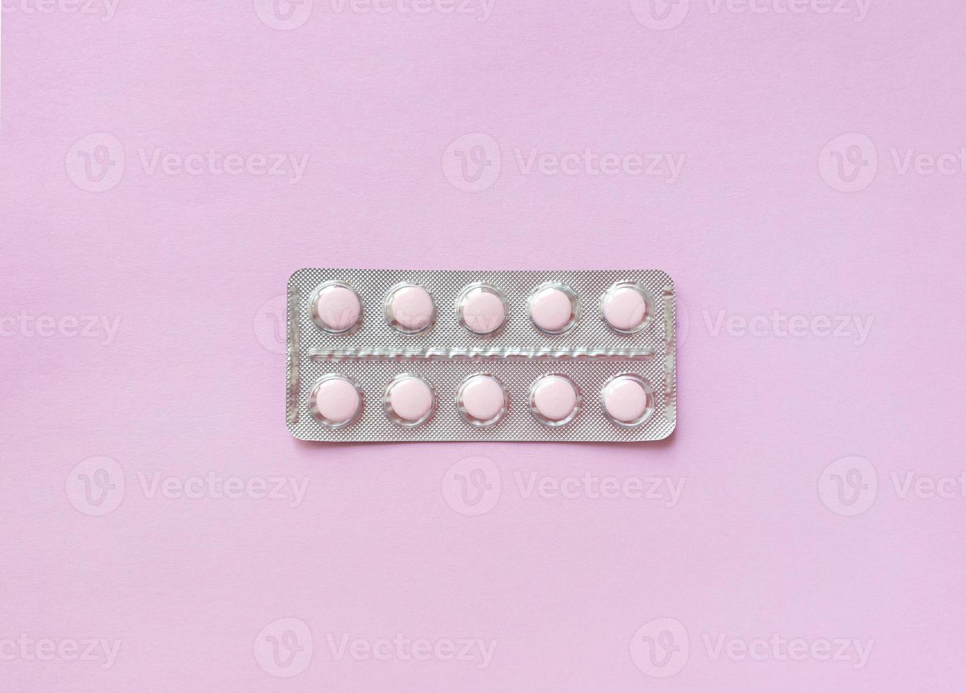 A blister of soft pink pills in the middle on pink background Monochrome simple flat lay with pastel texture Medical concept Stock photo