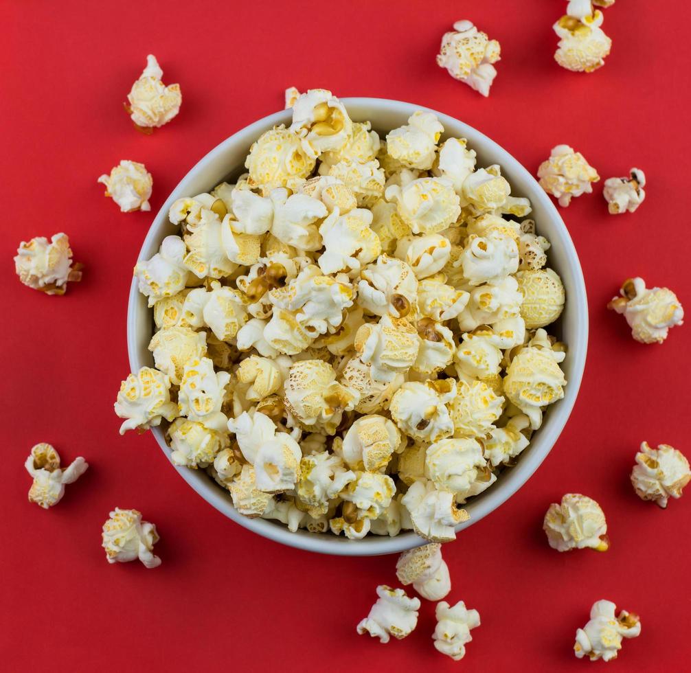 Cerca de palomitas de maíz con champiñones en un recipiente blanco con fondo rojo. foto