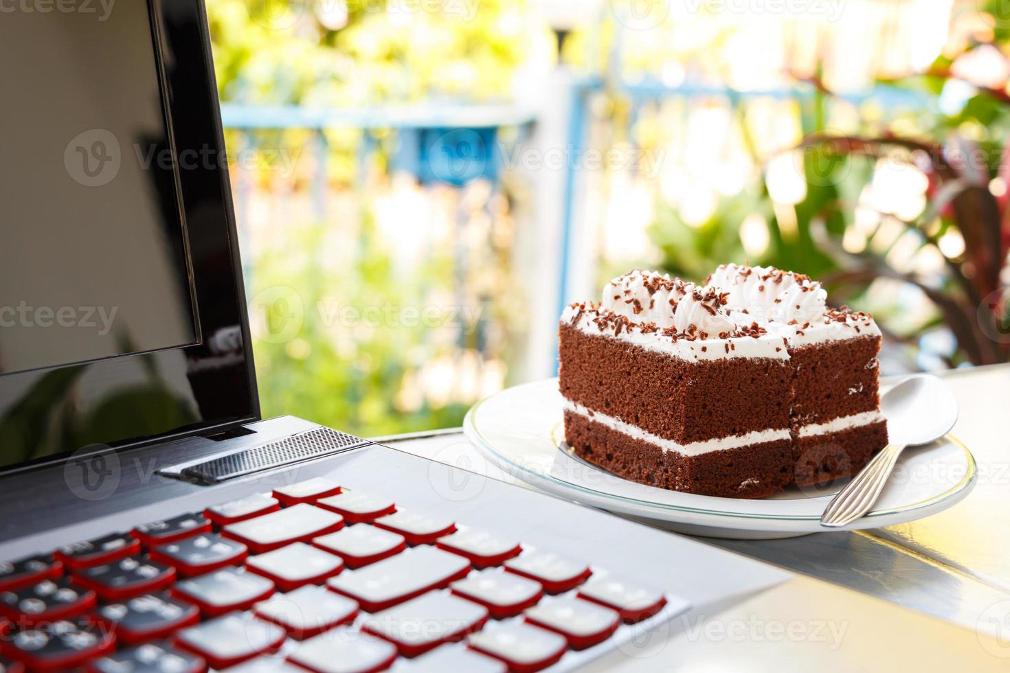 Tartas de chocolate con crema blanca en la parte superior y un ordenador portátil en casa foto