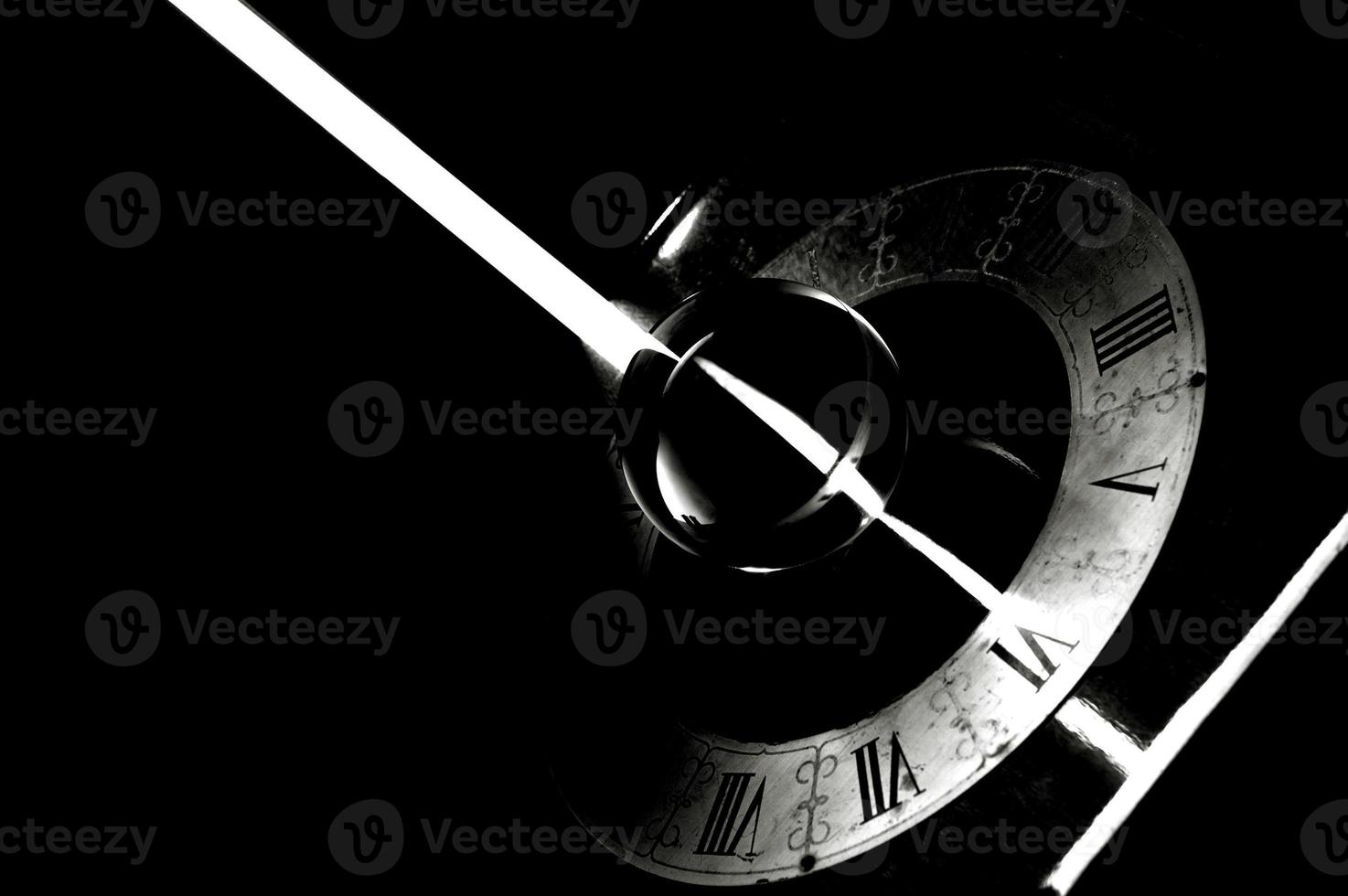 A vintage clock with a bright ray of light in black and white photo