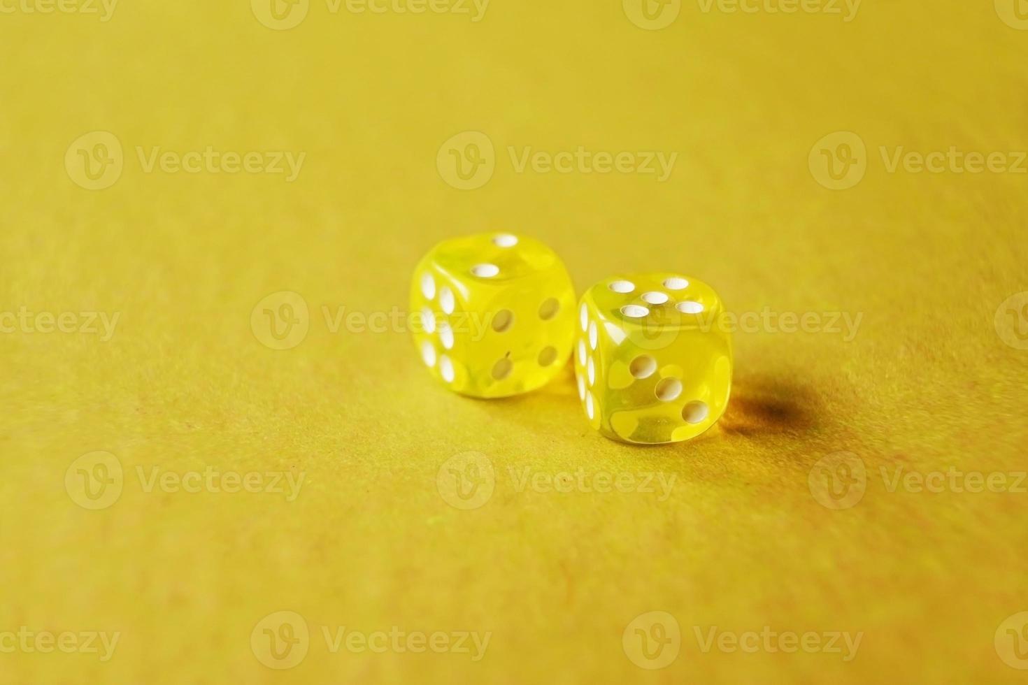 Una macro monocromática vibrante con profundidad de campo sobre dos dados de juego de vidrio amarillo con dos números dos y cinco sobre un fondo amarillo foto