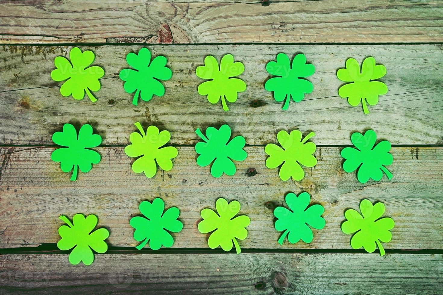 Green clovers over an old wooden table photo