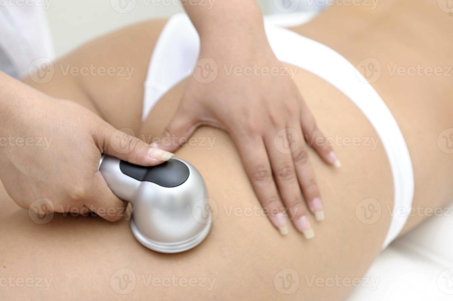 Primer plano de cosmetología de esteticista haciendo tratamiento de depilación láser en el hermoso cuerpo femenino eliminando el vello en la piel sedosa foto