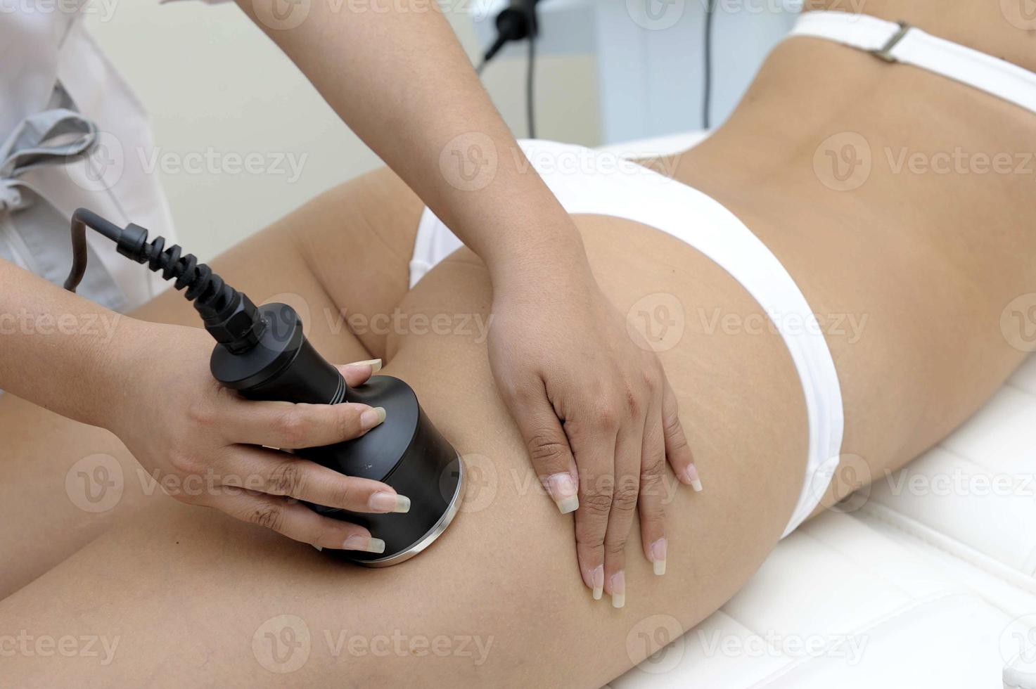 Primer plano de cosmetología de esteticista haciendo tratamiento de depilación láser en el hermoso cuerpo femenino eliminando el vello en la piel sedosa foto