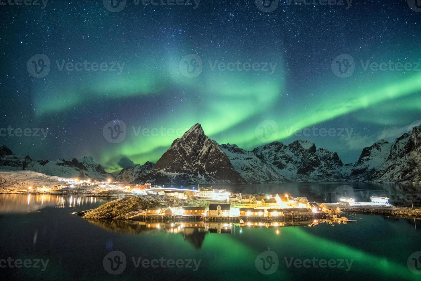 Aurora borealis over mountains in scandinavian village glowing photo