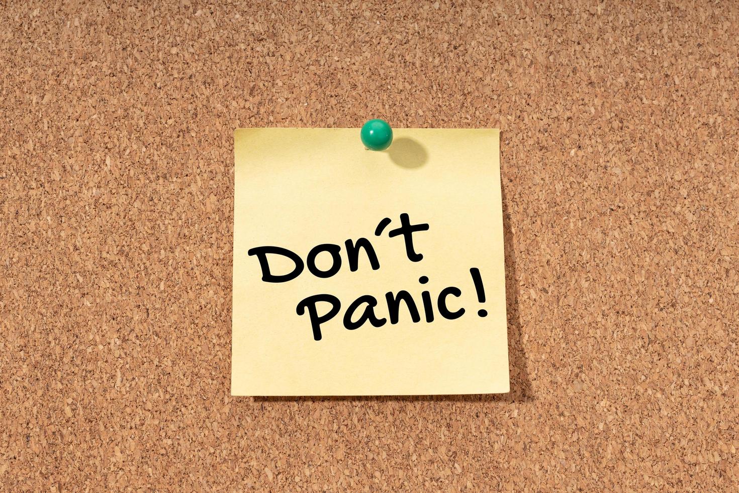 Dont panic message on yellow note on cork board photo