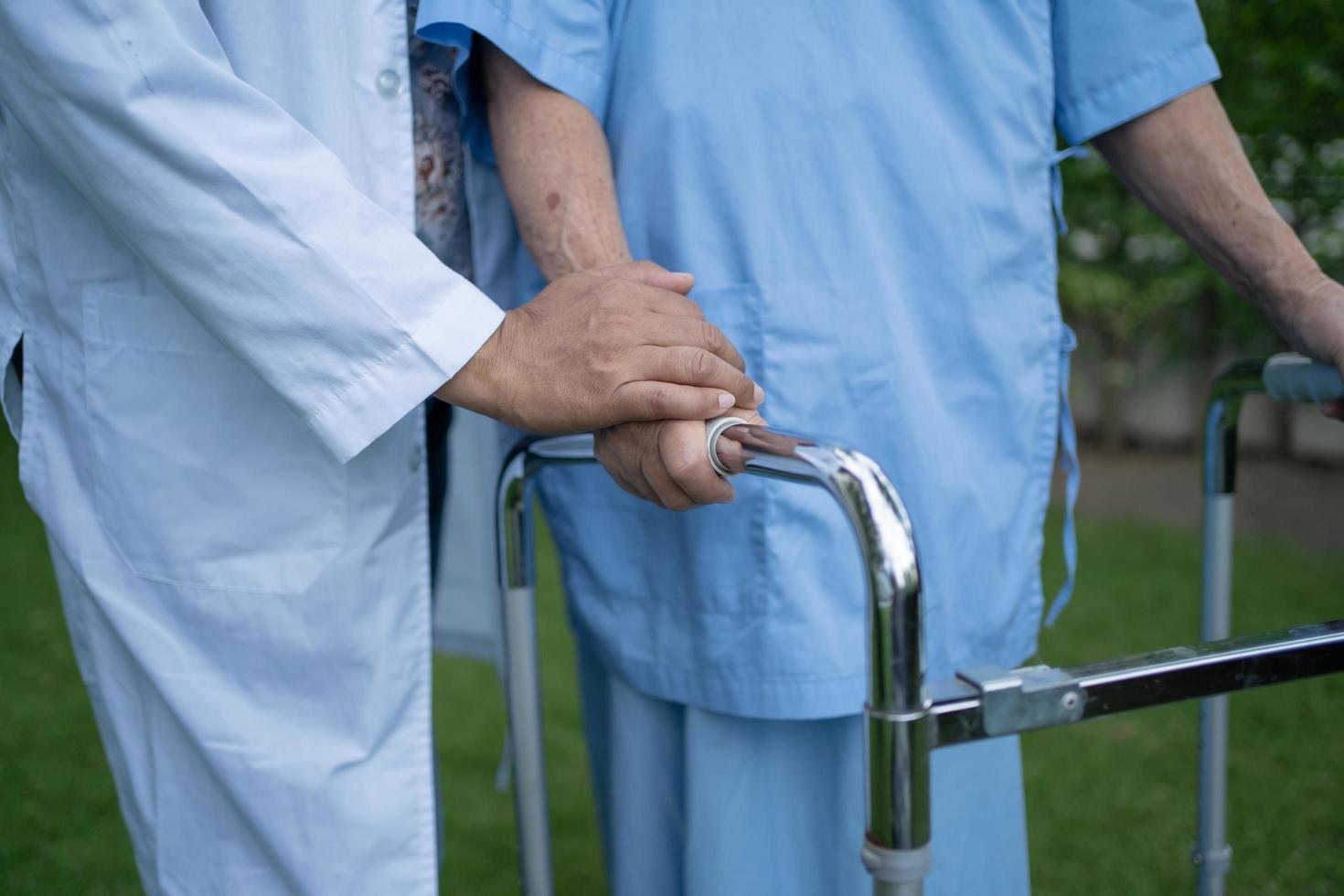 Help and care Asian senior or elderly old lady woman use walker with strong health while walking at park in happy fresh holiday photo
