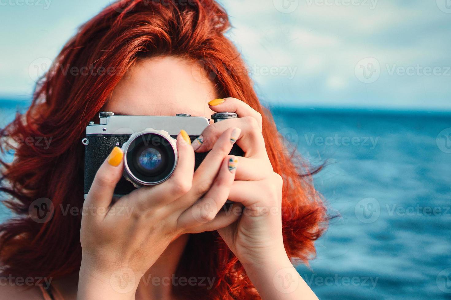 Female redhead person at ocean with camera photo