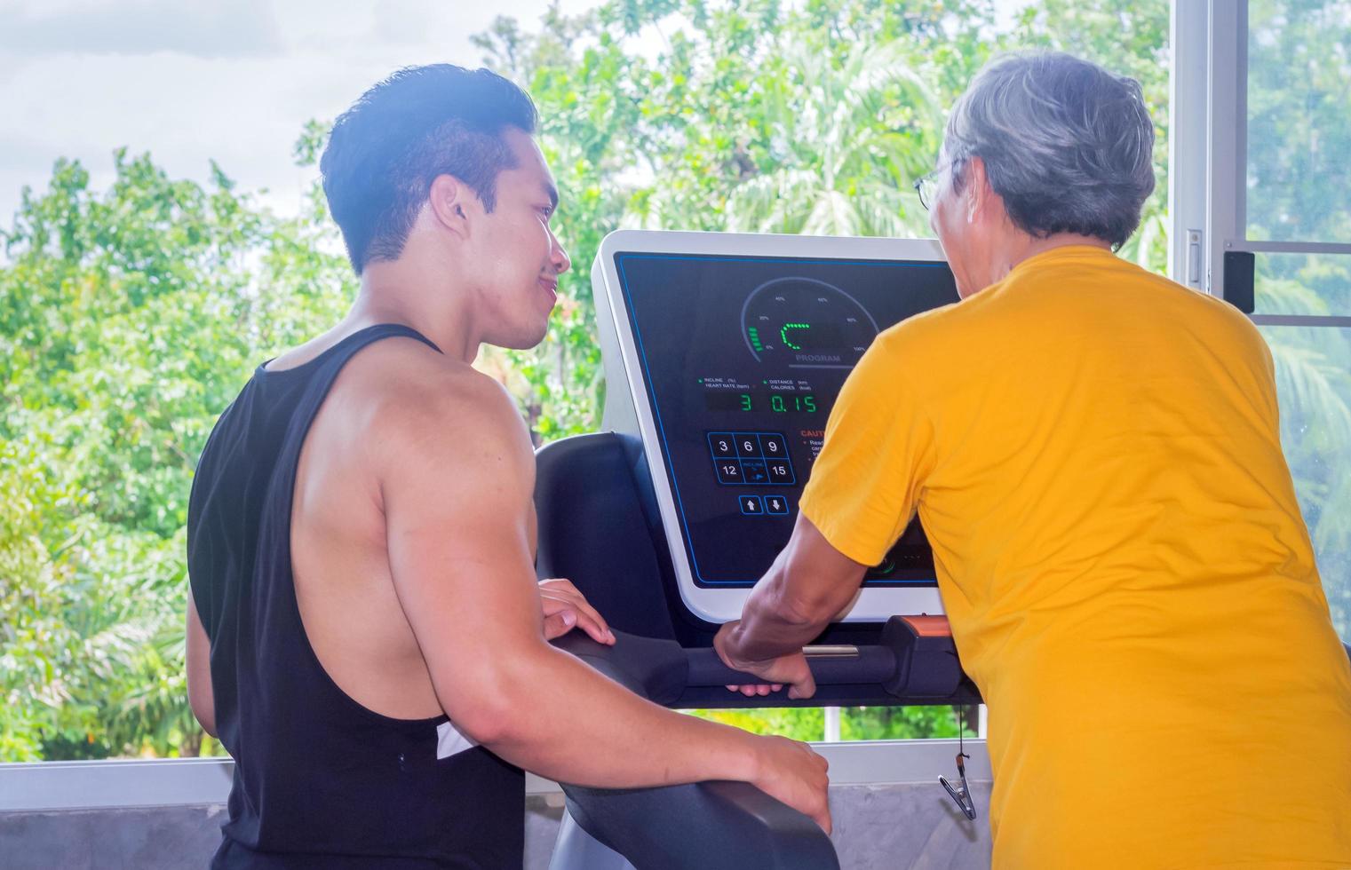 Anciano asiático haciendo ejercicio en un gimnasio con un entrenador foto