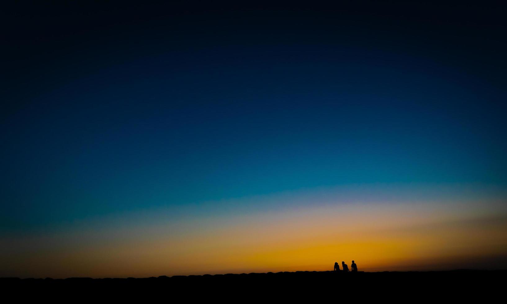 imagen de estilo de bellas artes de tres personas esperando la puesta de sol foto