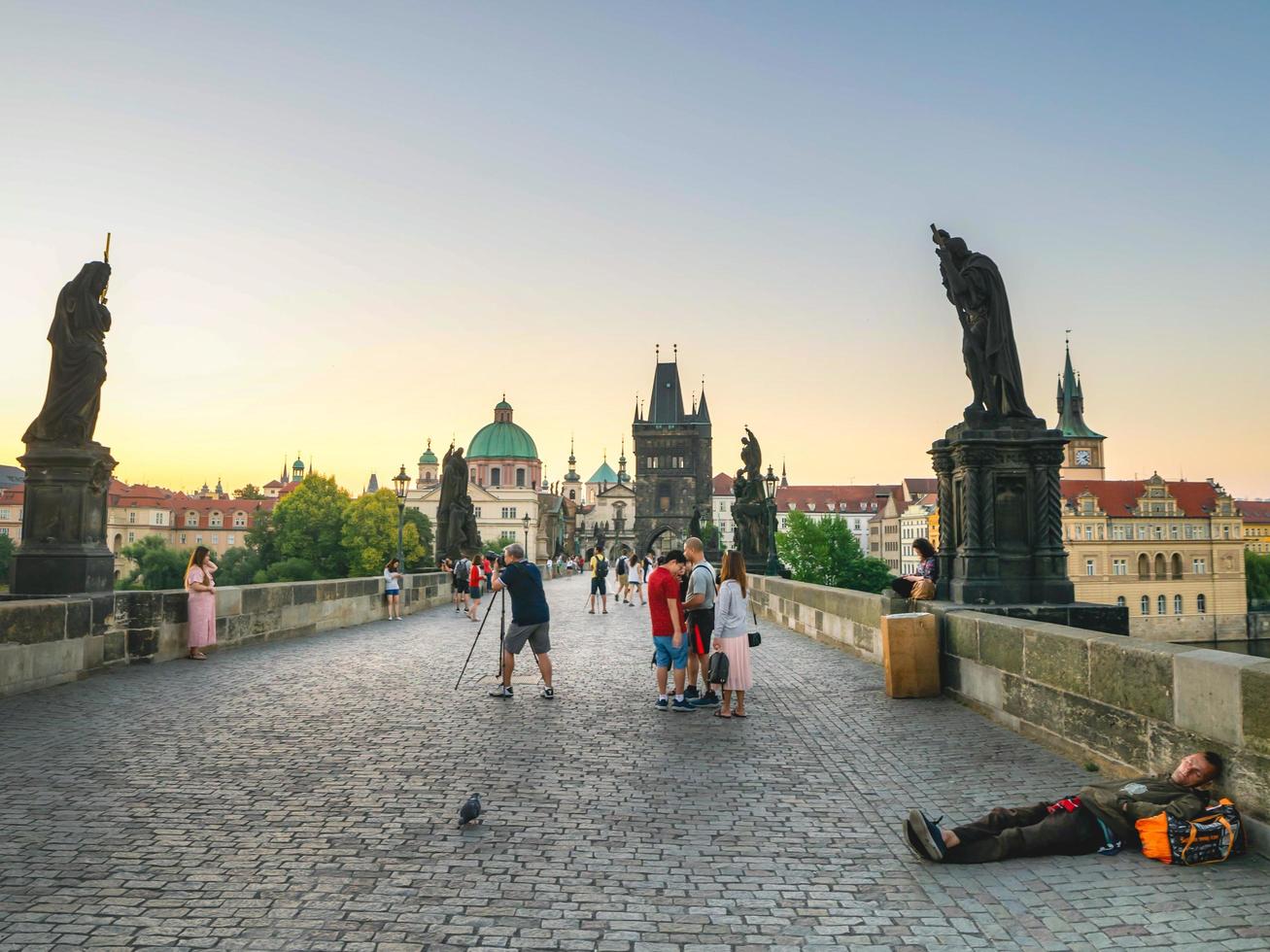 Prague, 2018- Sleeping homeless with tourists around on Charles bridge in Prague early in the morning photo