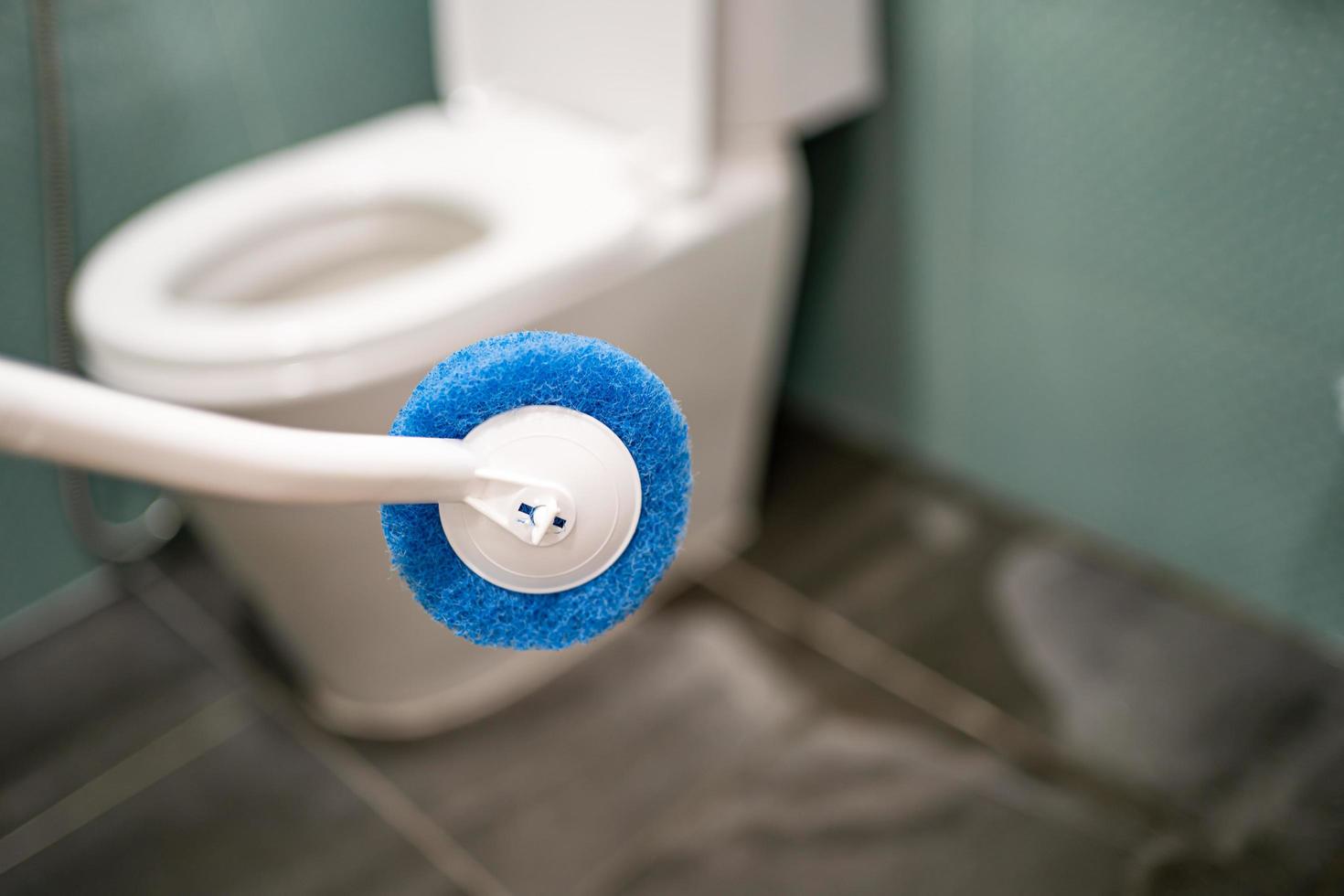 Maid cleaning toilet bowl with brush in bathroom at home photo