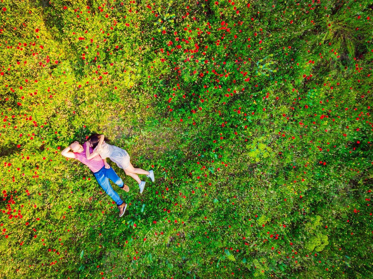 Happy couple together in love isolated laying in green nature field on summer day photo