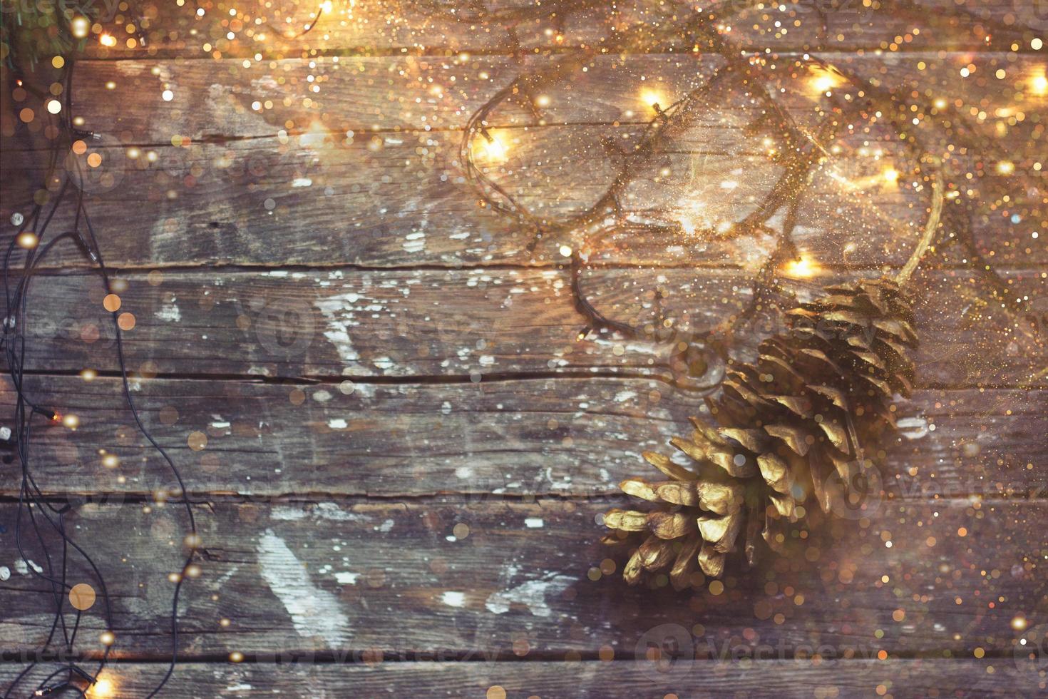 Fondo de Navidad luces de Navidad y cono de pino sobre fondo de madera oscura con brillo dorado foto