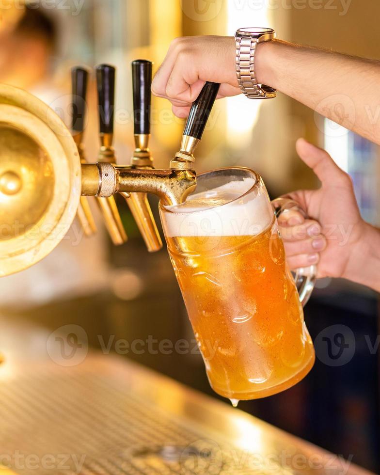 hombre vertiendo y llenando una jarra de cerveza foto