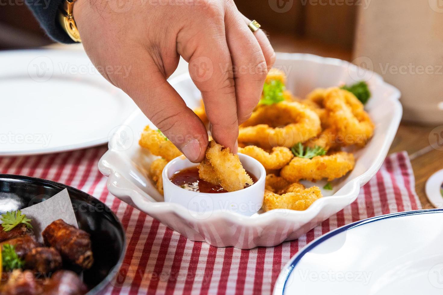 Man dipping calamari ring into the ketchup photo