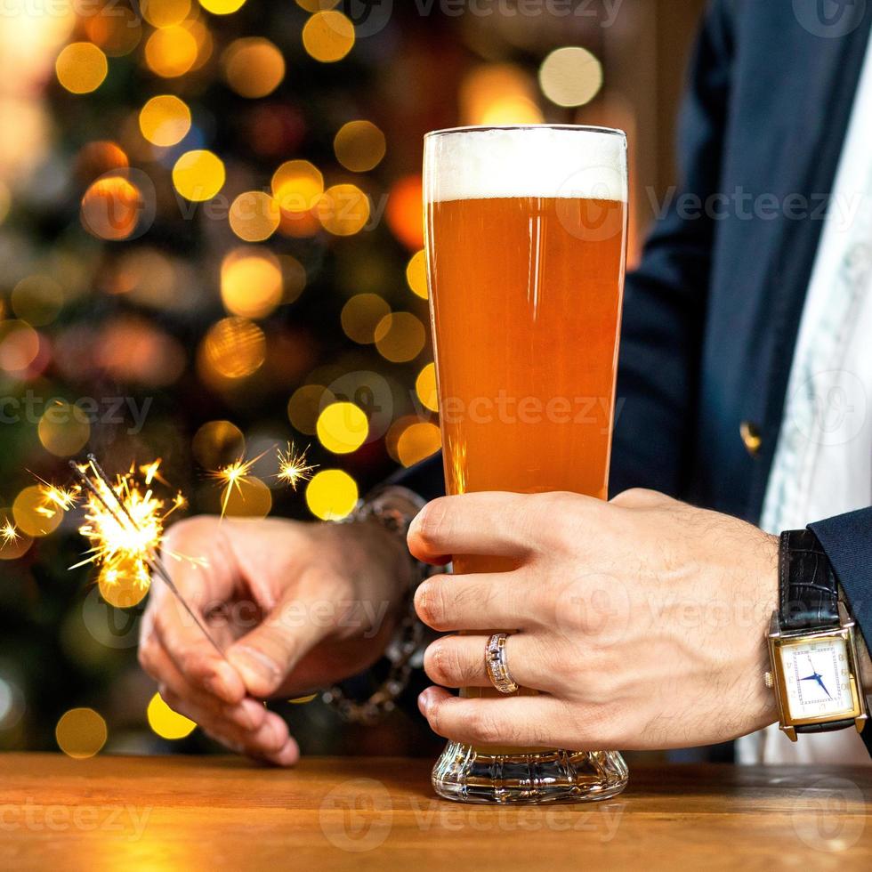 Traje con hombre sosteniendo un vaso de cerveza y bengalas encendidas foto