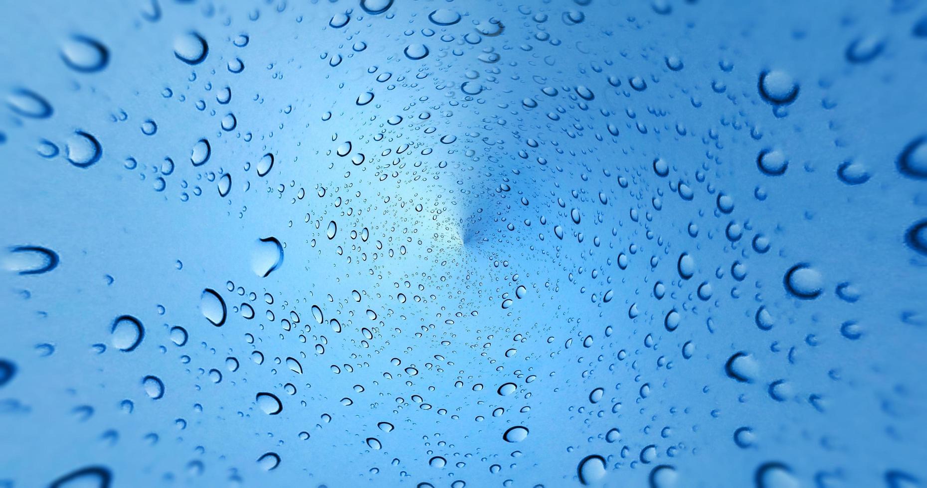 Gotas de lluvia sobre fondo de ventana de vidrio azul foto