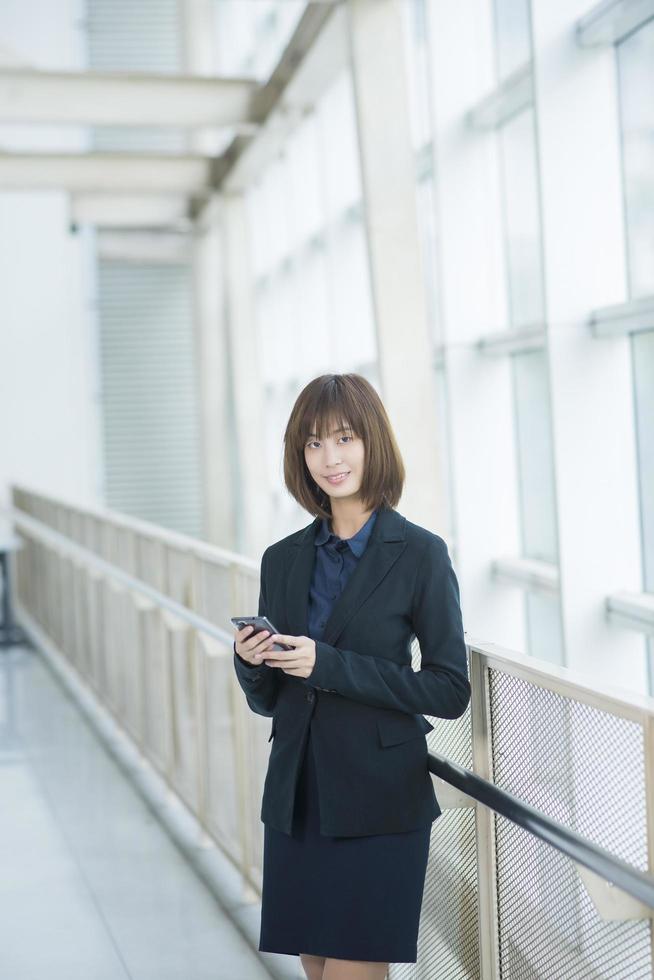 Attractive asian business woman using on smartphone outside Office photo