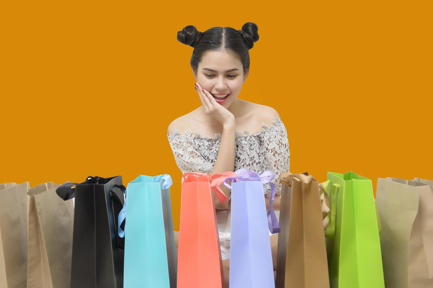 Attractive shopper woman holding shopping bags on yellow background photo