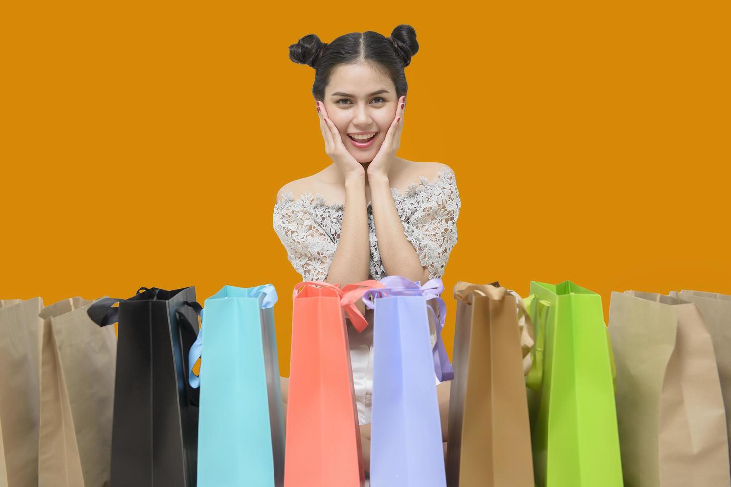 Attractive shopper woman holding shopping bags on yellow background photo