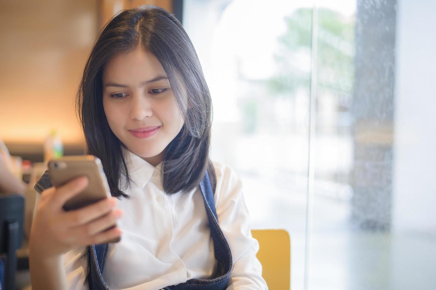 Attractive woman checking her messages on smartphone while sitting on coffee shop photo