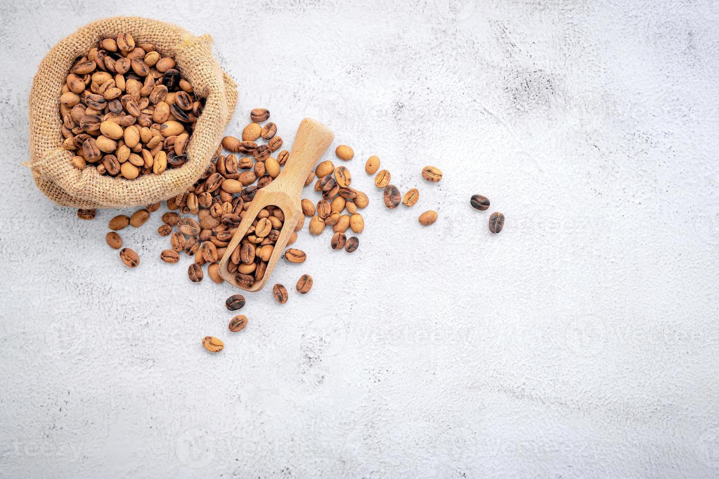 Roasted coffee beans with scoops setup on white concrete background photo