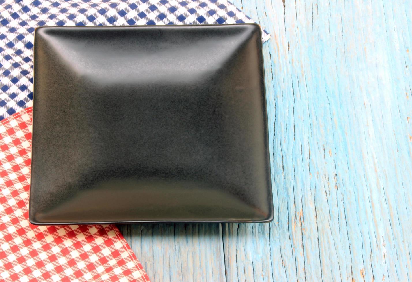 Black plate on tablecloth on wood table background photo