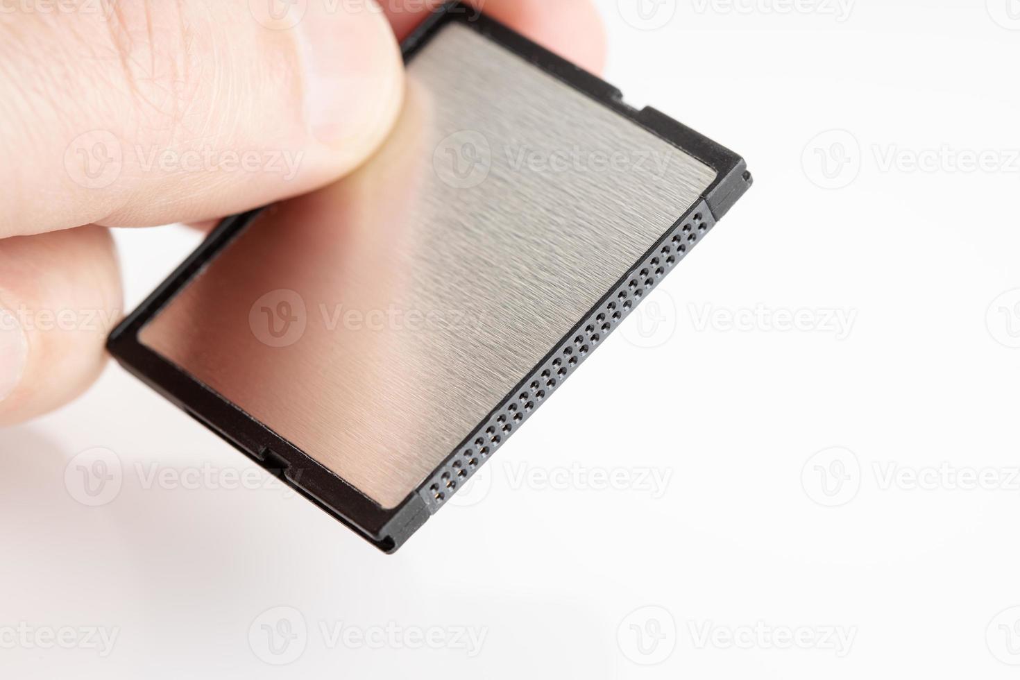 Hand holding a compact flash memory card on white background photo