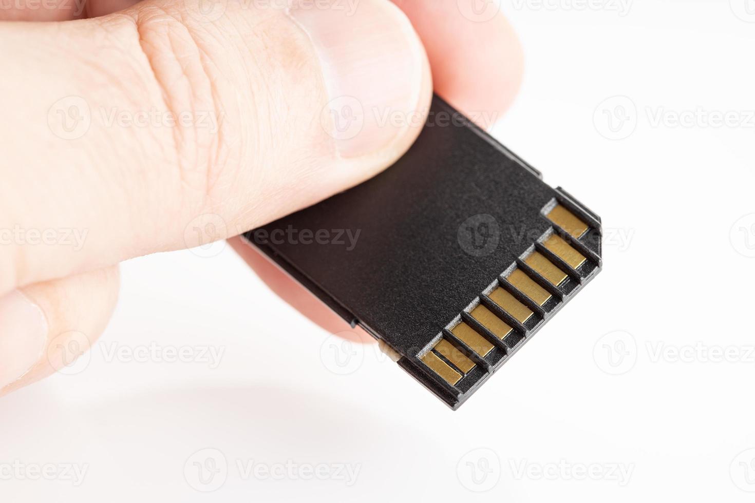 Hand holding a SD memory card on white background photo