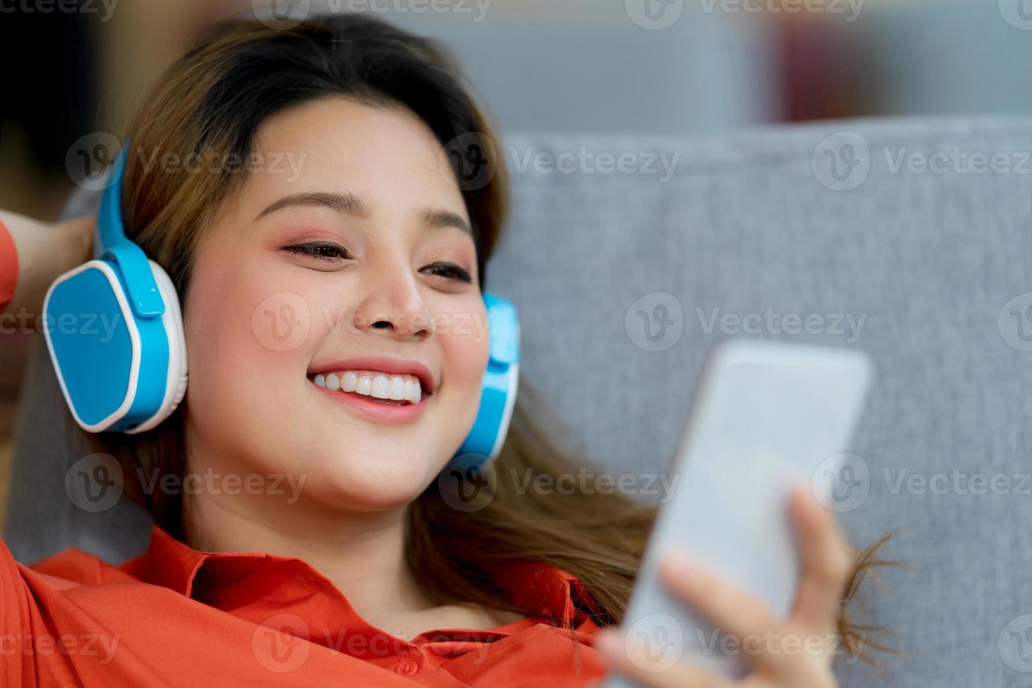 Retrato de joven bella mujer disfrutando de la música con cara sonriente sentado en la oficina creativa o cafetería foto