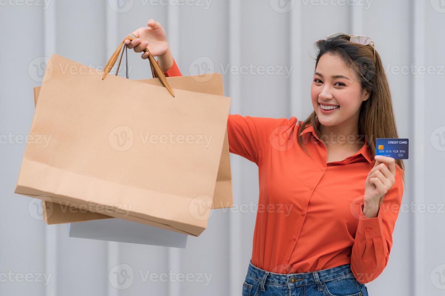 Retrato al aire libre de mujer feliz sosteniendo bolsas de compras con tarjeta de crédito foto