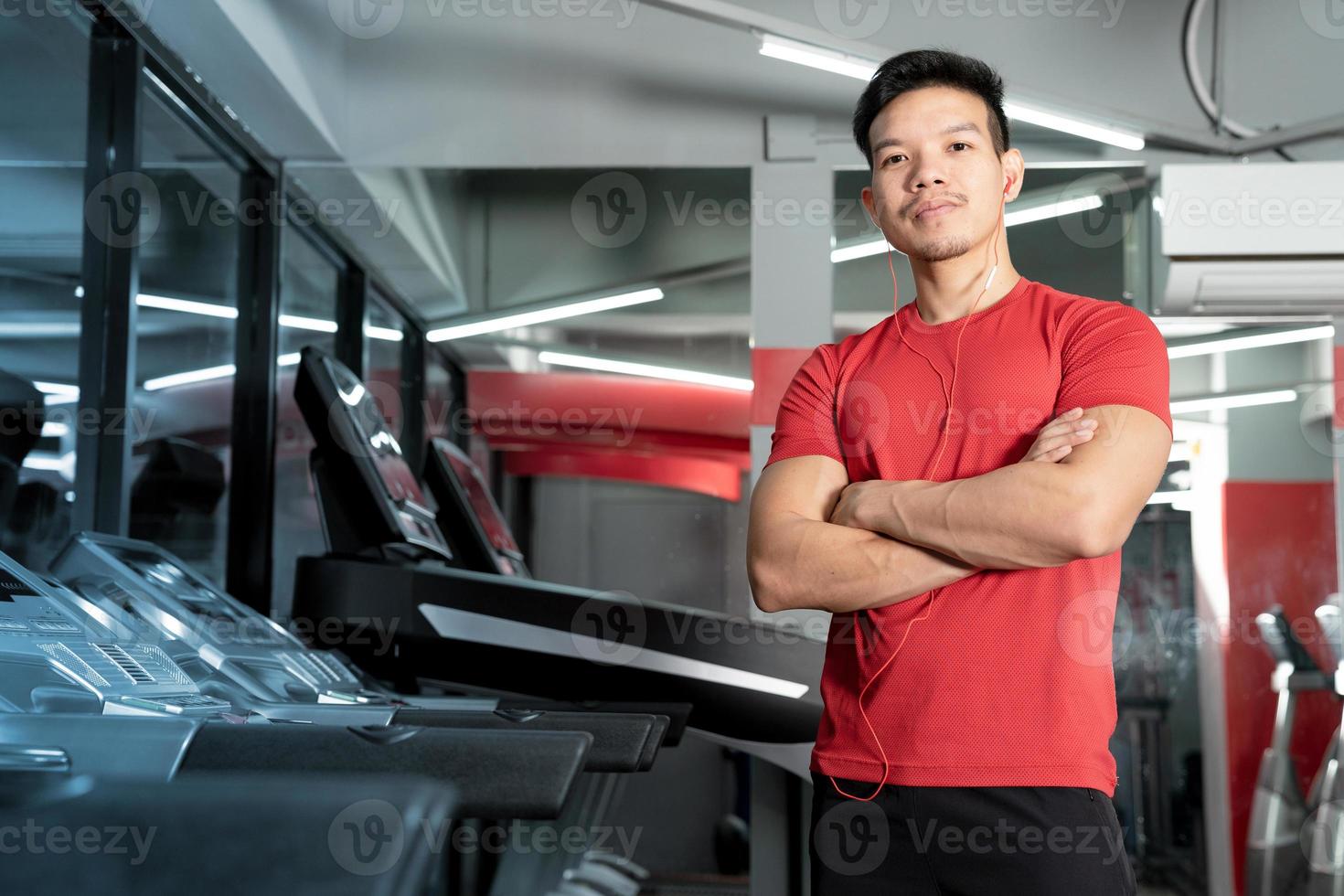 Athletic young man standing with arms crossed in gym photo