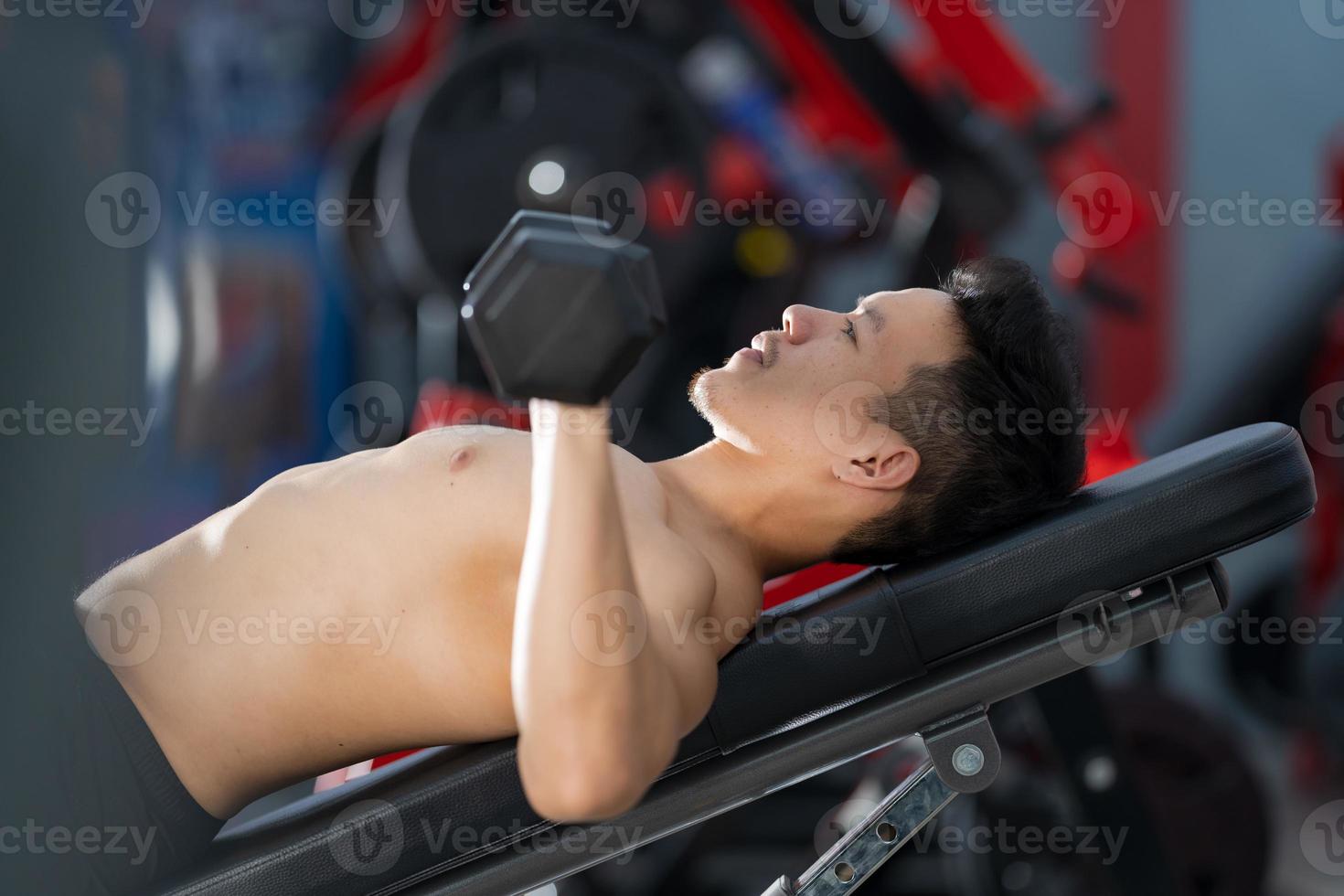 Sporty man training with dumbbell in gym photo