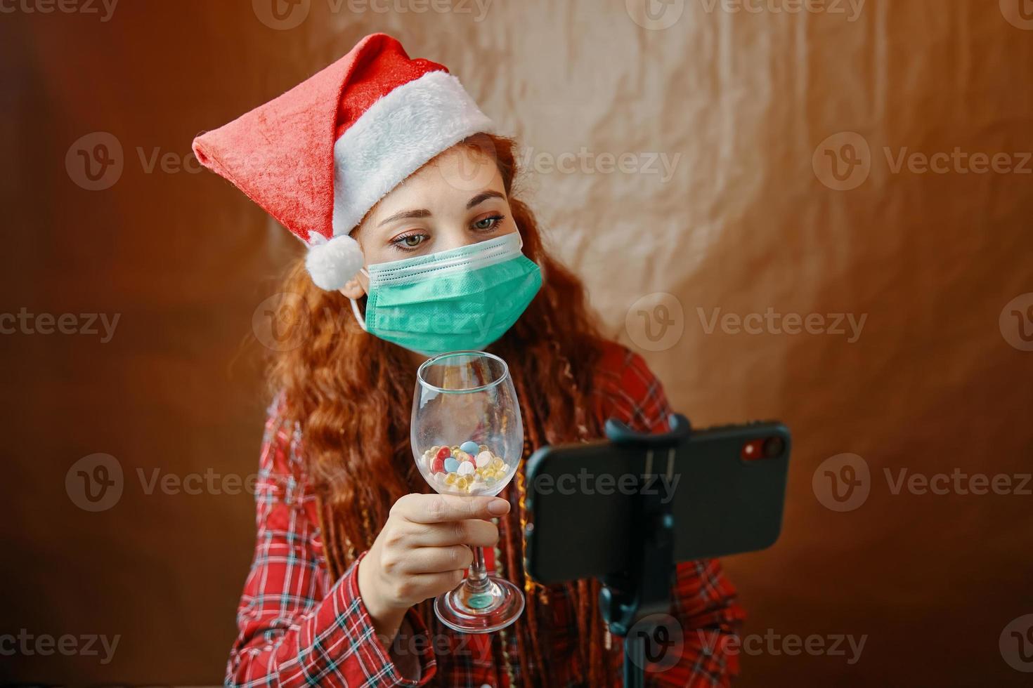 Mujer con máscara médica hacer videollamada navideña foto