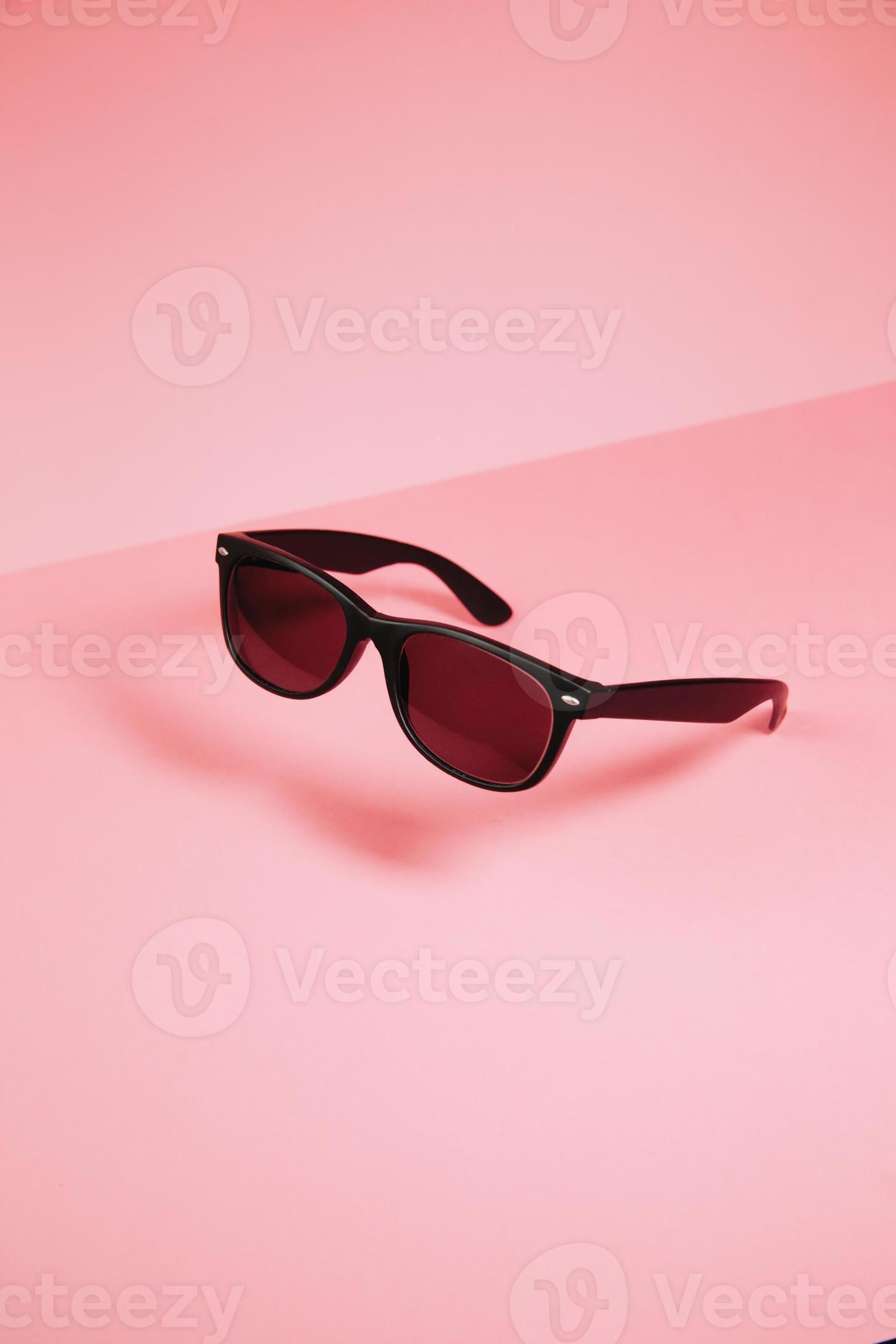 Pair of sunglasses over a pastel pink background with copy space