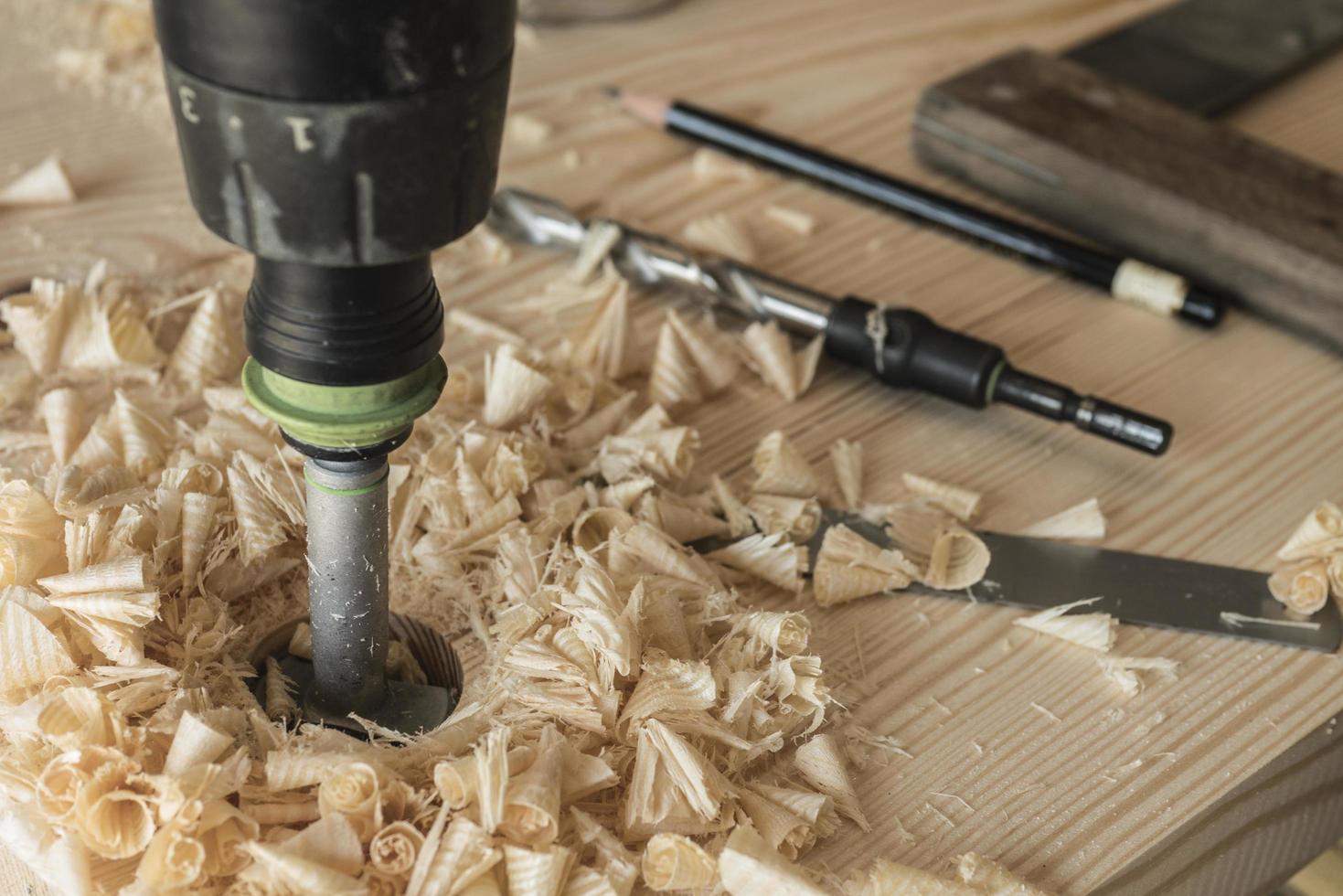 The joiner drills a workpiece of wood with a drill photo