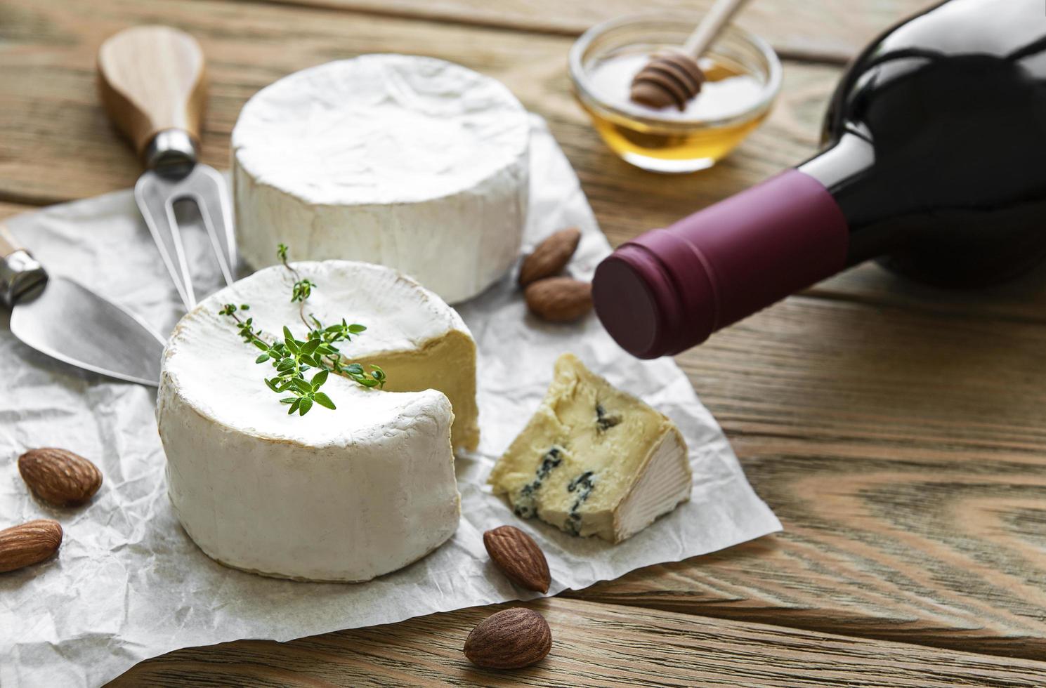 Various types of cheese, blue cheese, bree, camembert, and wine on a wooden table photo
