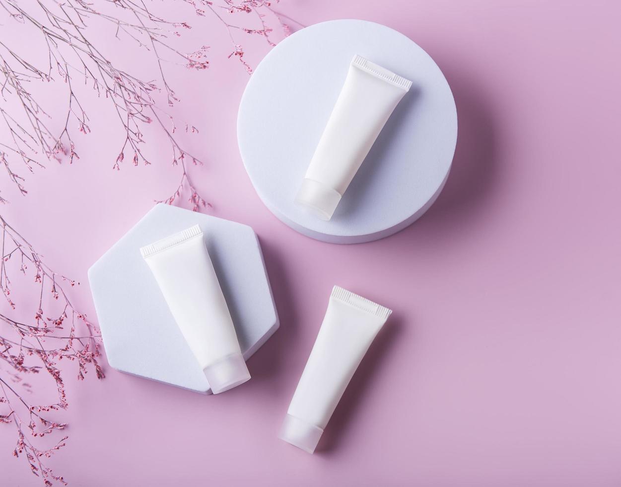 White tubes of cream on a pink background photo