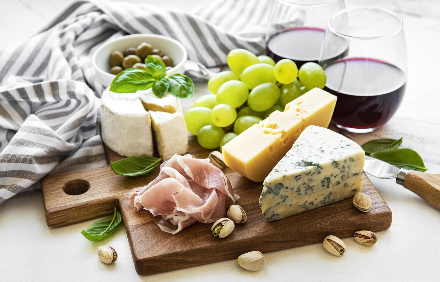 Various types of cheese, grapes, wine and snacks photo