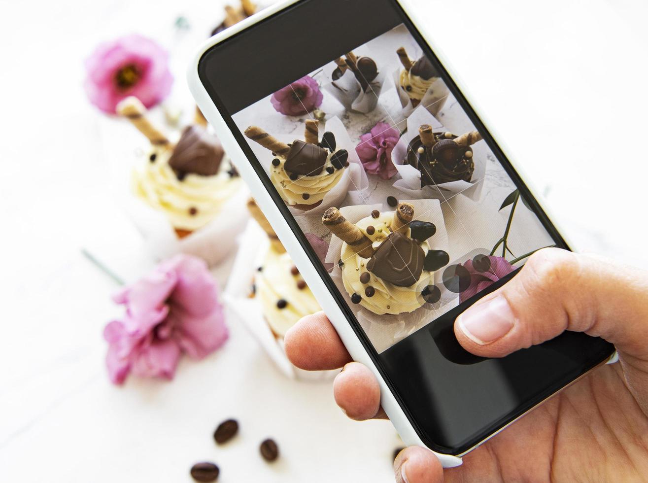 Girl makes a photo of cupcakes on a smartphone