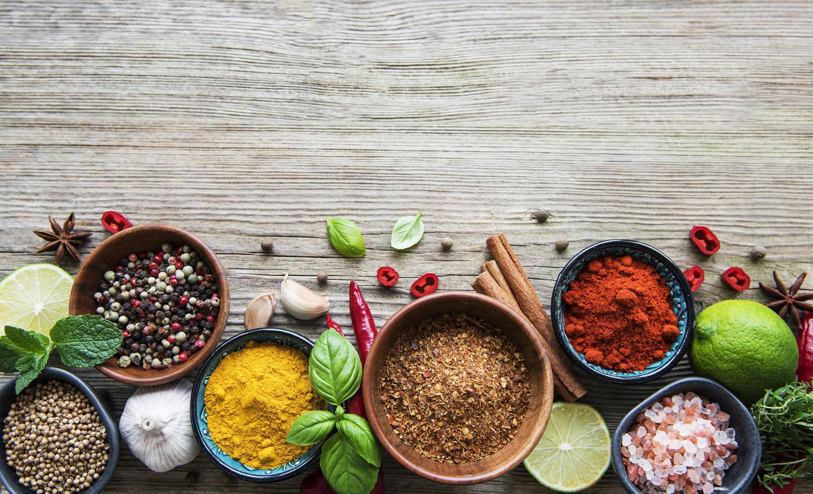 A selection of various colorful spices on a wooden table in bowls photo