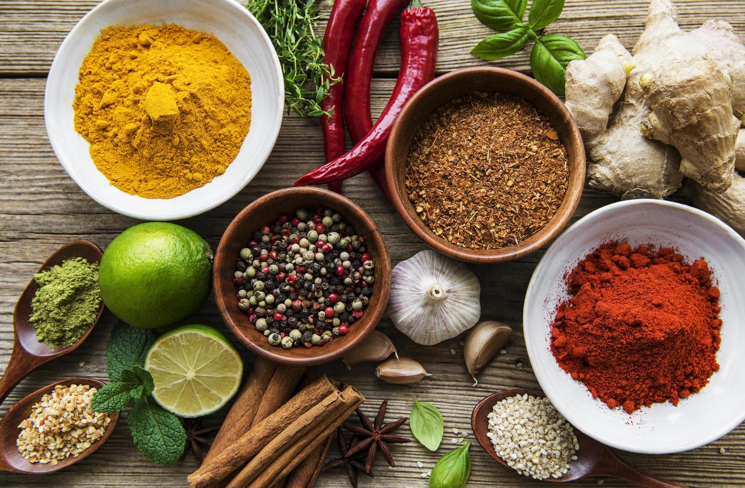 A selection of various colorful spices on a wooden table in bowls and spoons photo