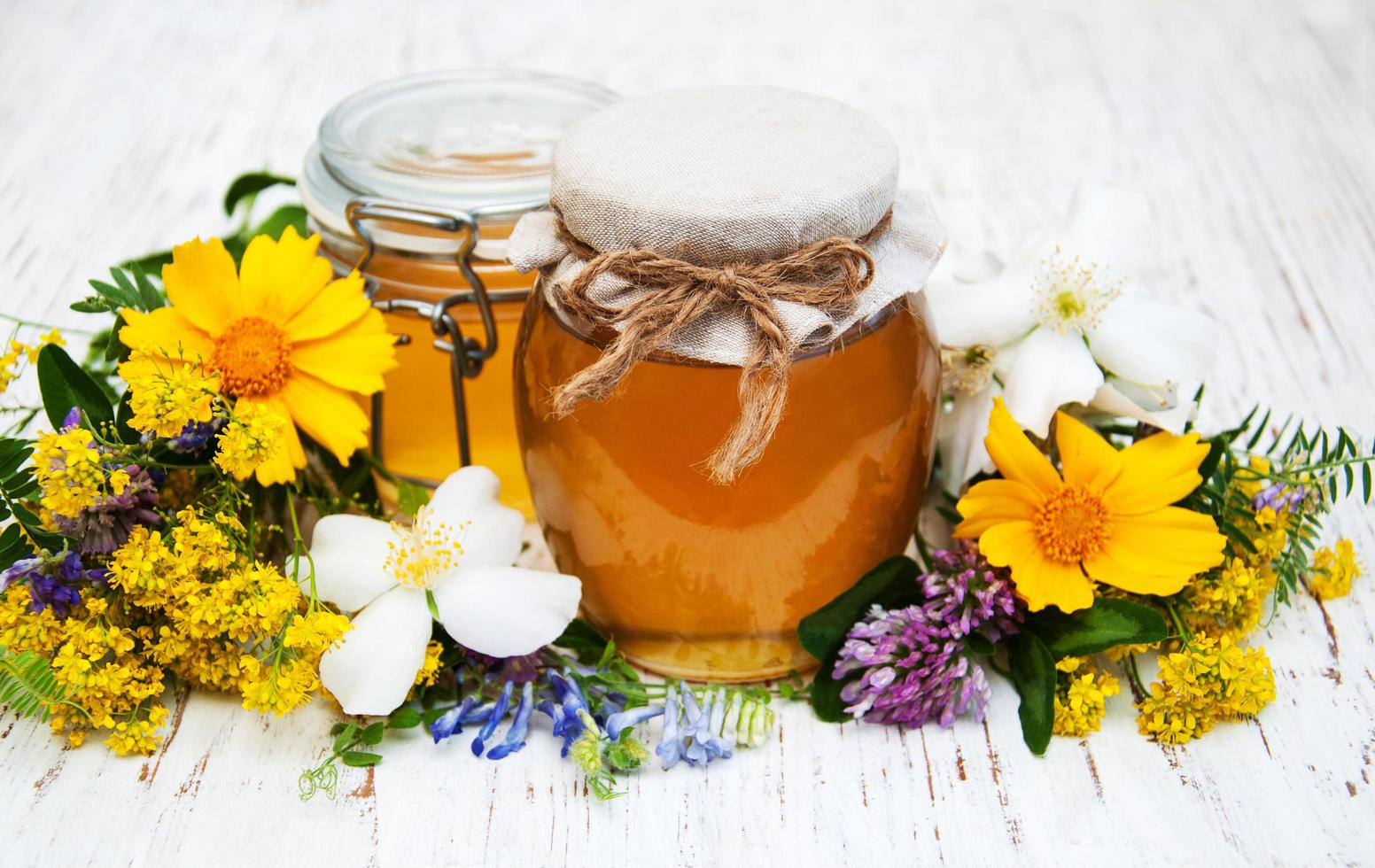 Honey and wild flowers on a wooden background photo