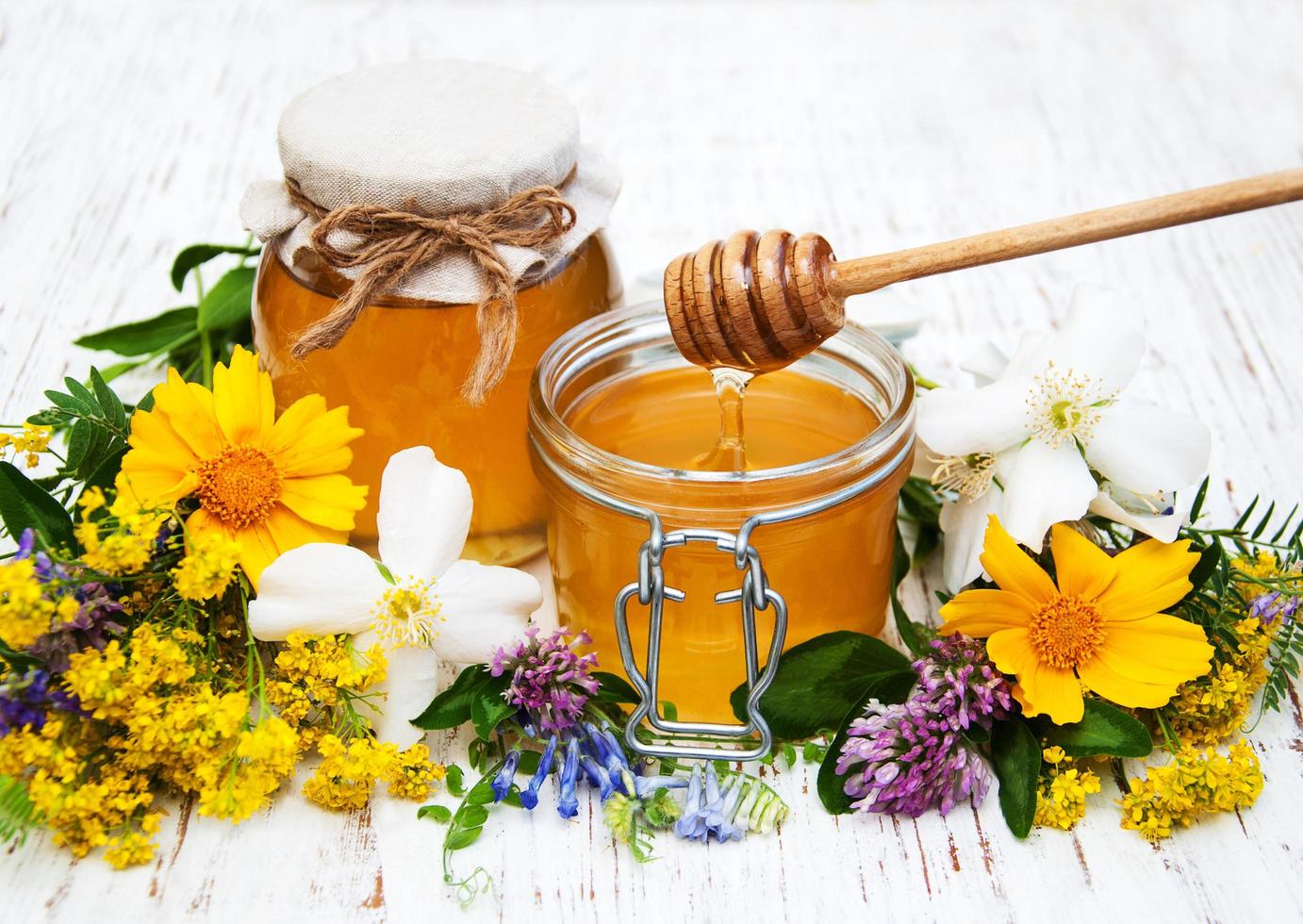 Honey and wild flowers on a wooden background photo