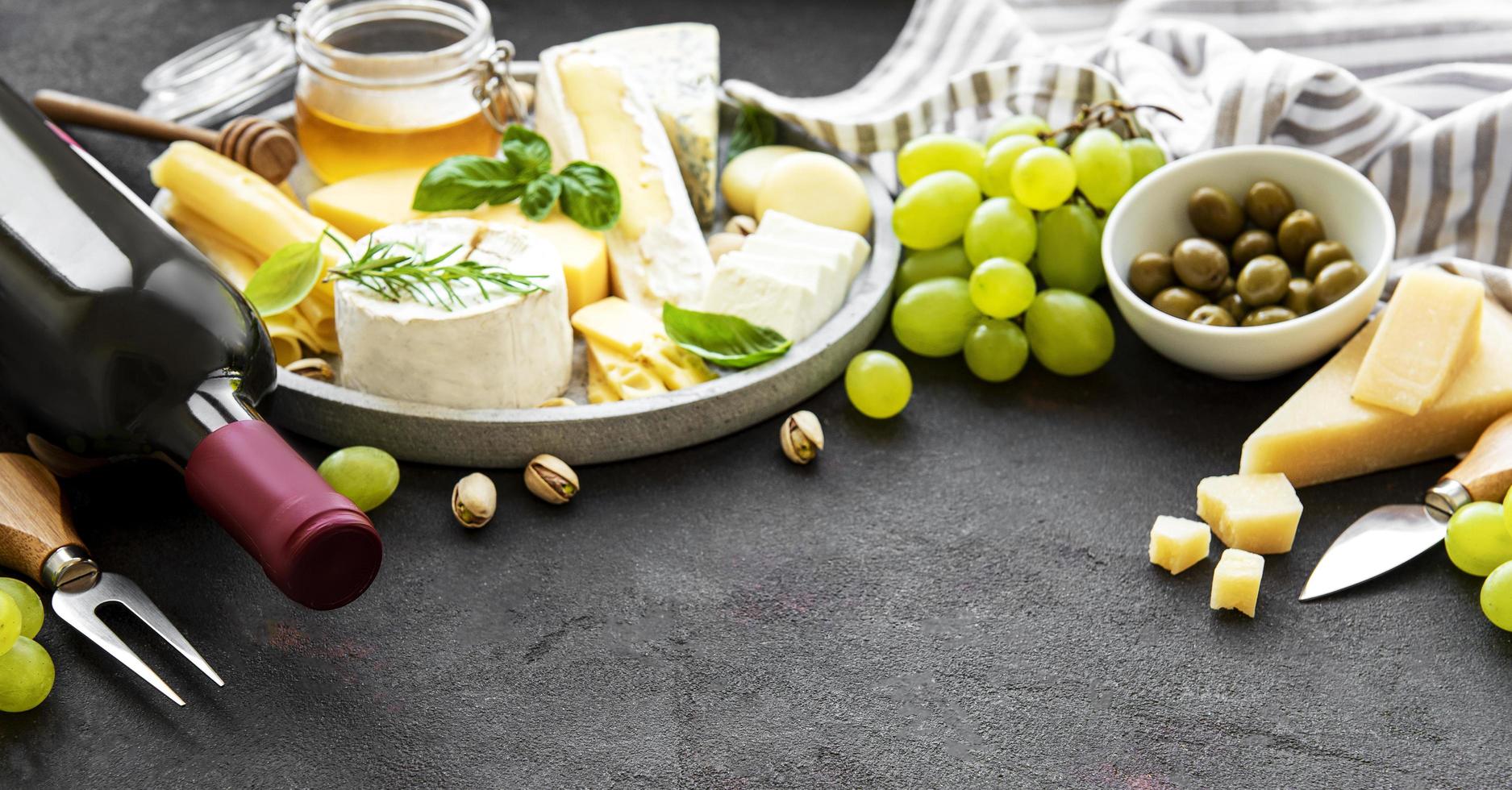 Various types of cheese, grapes, wine and snacks photo