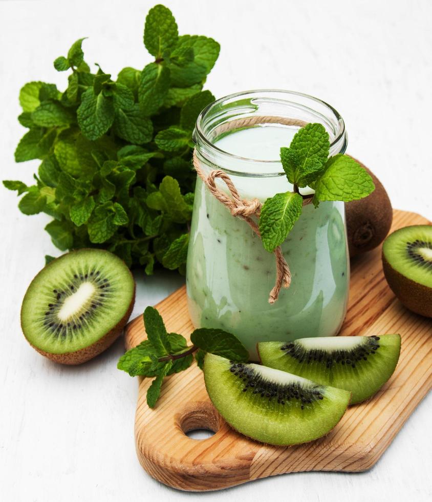 Kiwi smoothie in a glass on an old white wooden background photo