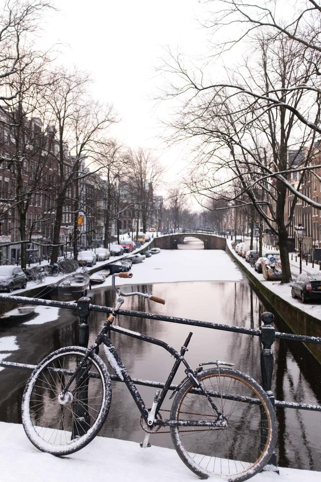 Bicicleta y canal en Amsterdam en la nieve. foto