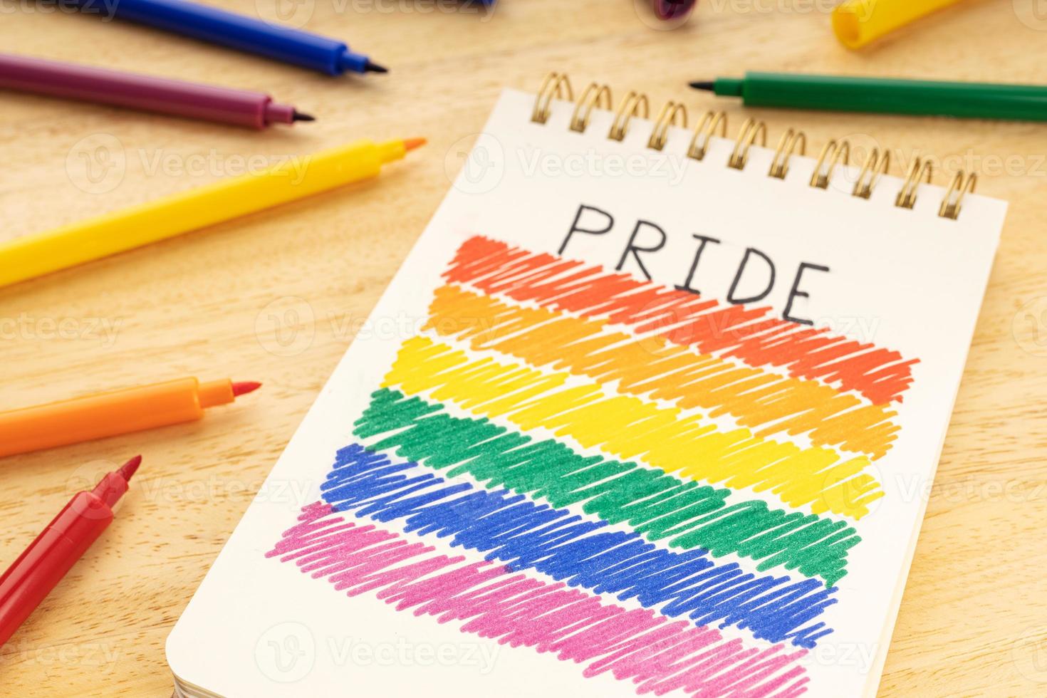 Notebook with LGBT rainbow flag drawing and marker pens on wooden table photo