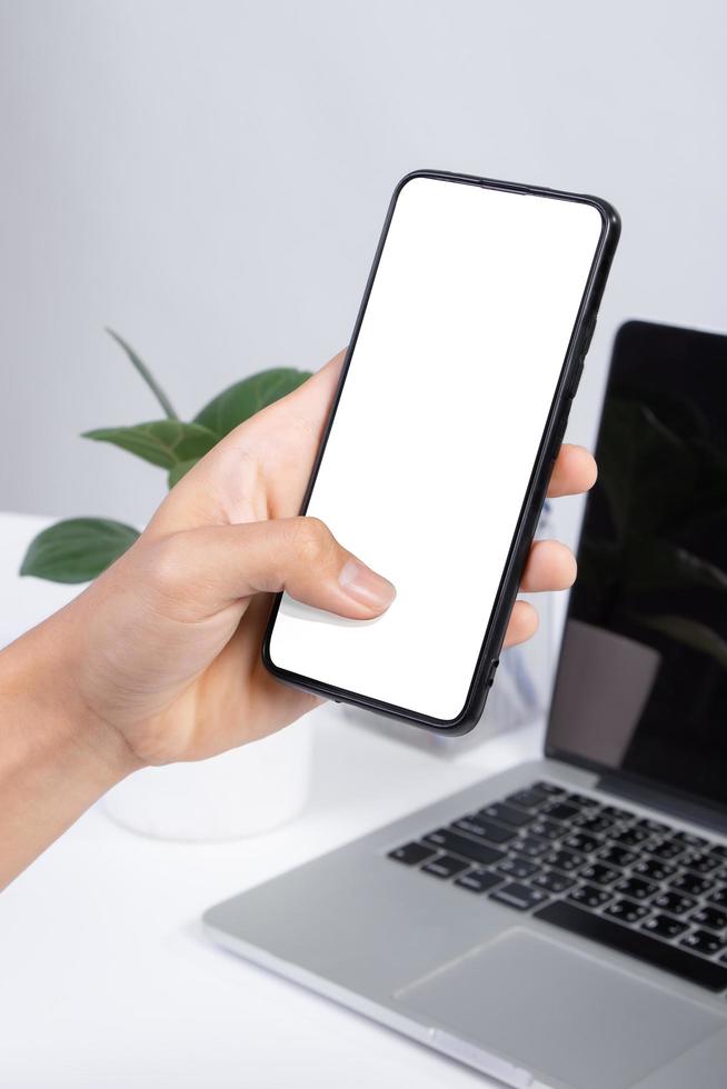 Hombre usando una pantalla en blanco de teléfono inteligente simulacro en el escritorio de oficina blanco foto